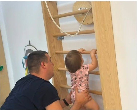 Tata pomaže bebi da se penje uz švedske lestve
